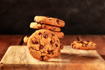Chocolate chip cookies on a dark rustic wooden background, with a place for text
