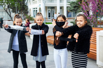Group of pretty preteen girl walking outdoor in mask to protection face from virus. Kids dressed black and white clothes kids. Children don't like new fashion on epidemic situation in world
