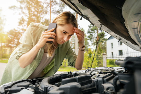 Woman Looking At Broken Car Engine And Talking On The Phone