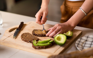 Woman making avocado peanut butter toast for a healthy breakfast