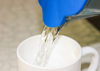 Purified water from the filter jug is poured into a drinking Cup.