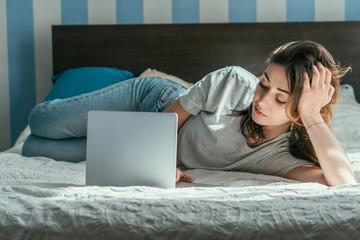 freelancer lying on bed and using laptop while working from home