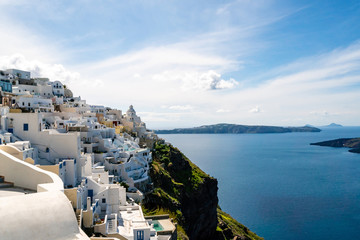 Sunshine on white houses near tranquil Aegean sea against sky with clouds in Greece