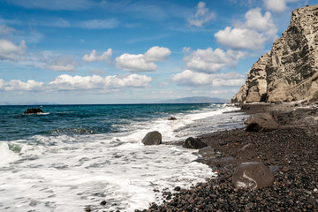 Blue Aegean sea near rocks against sky with clouds