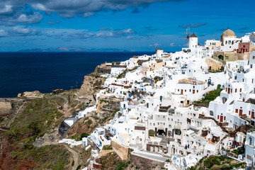 White houses near tranquil sea against sky with clouds in Santorini