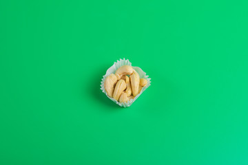 portion of cashews in a paper muffin cup on a green background