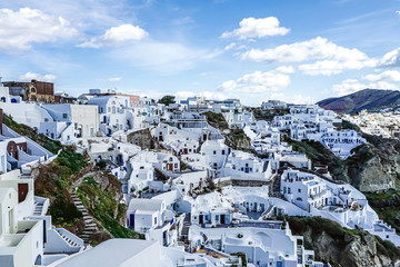 Fototapeta na wymiar White houses on hill against sky with clouds in Greece