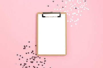 Clipboard mockup with blank paper. Frame made of shiny stars on pink pastel background. Holidays concept.