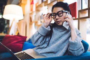 Smart female freelancer talking on smartphone