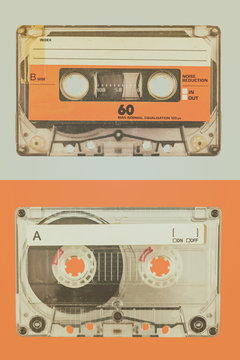 Two old audio compact cassettes on a blue with orange background