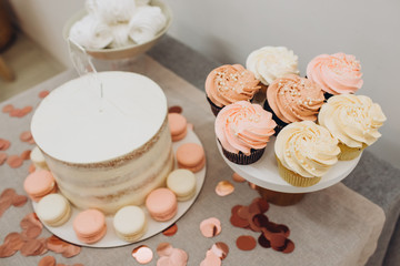 Birthday cake. Garland - happy birthday, hanging on the wall. Candy bar with cake, marshmallows, and cupcakes. Stylish decor for a children's party.