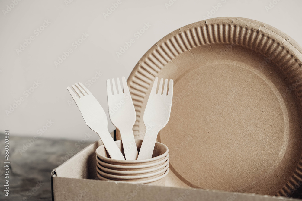 Wall mural wooden forks and paper cups with plates on box paper background. eco friendly disposable tableware. 