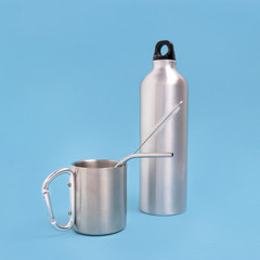 Stainless steel bottle, cup, drink tube and cleaning brush on a blue background. Zero waste concept.