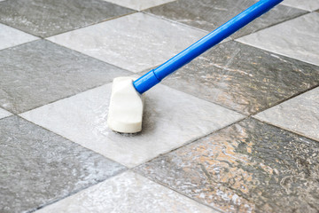 Cleaning the tile floor with floor scrubber brush.