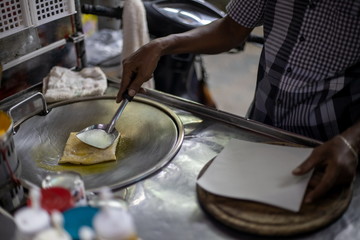 Thai man cooking and selling traditional Thai sweet pancakes on the street