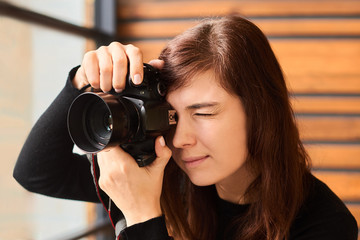 woman photographer taking photo with camera on professional photo shoot with day light near window