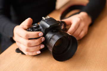 closeup of hand of young woman with camera in photo studio. photographer day concept