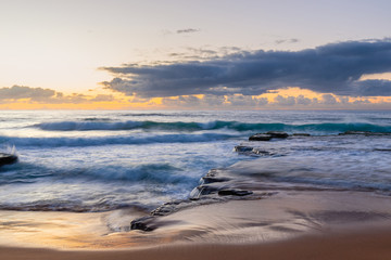 Fototapeta na wymiar Flow of water in the rock coastline under cloudy sky at Turimetta Beach, Sydney, Australia.