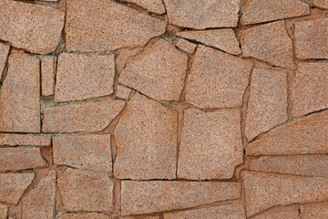 Natural texture and background. Wall of pieces of chipped stone slabs of red granite