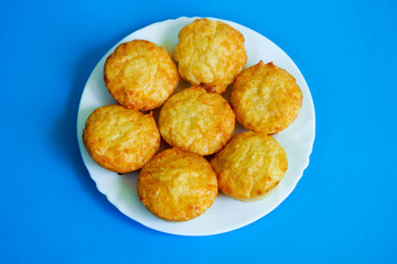 seven cheese muffins made of cottage cheese, eggs and rice flour on a white round plate on a blue background top view. gluten-free food prepared at home. bakery products