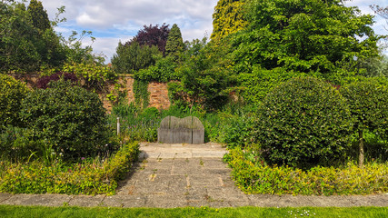 A garden landscape design featuring lawns, trees, evergreen topiary bushes and flower bed in England. english backyard