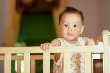 Portrait of baby toddler in baby walker. Expressive child plays toys.