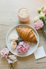 Croissant, cup of coffee and flowers. Beautiful composition. Flat lay. Coffee shop concept.
