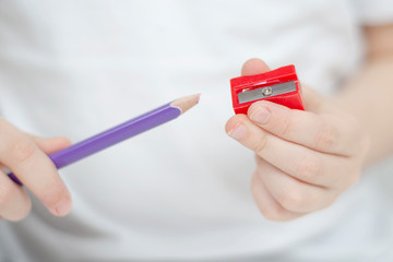A little girl wants to sharpen a broken colored pencil. Children's development. Selective focus