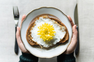Conceptual image of having a fried egg toast for breakfast. Yellow chrysanthemum flower instead of yolk served on a white plate