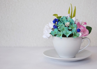 A white teacup full of flowers stands on a white background