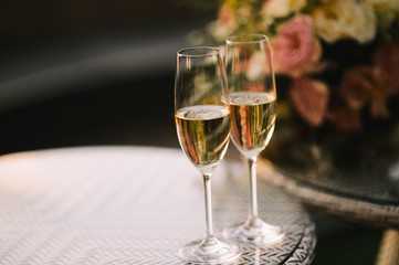 Two glasses of champagne stand on a table stand on a table.