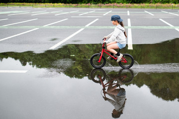 Obraz premium 水溜まりで自転車に乗る女の子