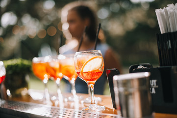 Glasses of aperol spritz with a straw for cocktails stand on a bar counter. 