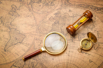 Old compass , magnifying glass and sand clock  on vintage map