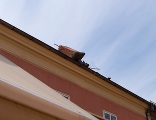 Fototapeta na wymiar Zagreb/Croatia-April 6th,2020: Broken off chimney dangerously hanging on the edge of the roof top above pedestrian street, damaged during strong earthquake