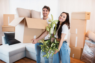 Happy couple with cardboard boxes in new house at moving day.