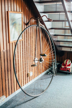 Old fashioned bicycle with one big and one small wheel under the stairs in a house.