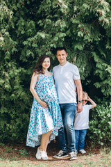 Fototapeta premium A young family and a son walk in nature. Husband and pregnant wife in spring park. happy family outdoor holidays.