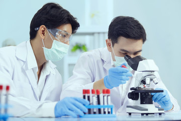 Two Male Scientists working in Lab while Checking Result of Blood Sample testing. Blue Tone. SARS-CoV-2 , Covid-19 THEME.