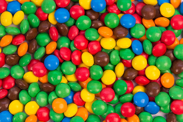 Fototapeta na wymiar Colorful candies closeup top view. Mouthwatering sweet balls in bright green, red, brown, blue, yellow, orange colors. Colorful and tasty sweetmeats background