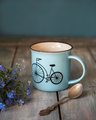 Coffee in a blue mug and a bouquet of forget-me-nots on a morning mood