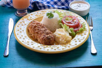 Food plate. Lunch. Breaded, rice, mashed potatoes and salad. Blue background.