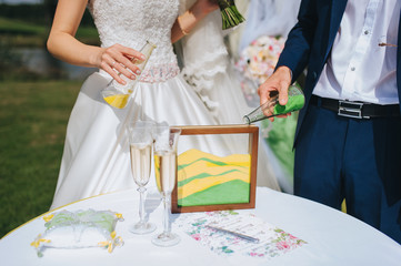 The bride and groom pour kinetic yellow and green sand into a glass tank. Ukrainian and European...