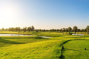 Beautiful, with green grass, golf course, with a pond, with sunny blue and clear sky. Portugal,...