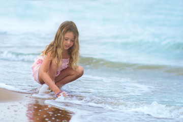 Fototapeta na wymiar young girl is plaing at the seaside in Lignano, the wave splash girl