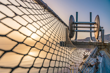 Fisherman is fishing fresh fishes using yellow fishing nets, on fishing boat, Crete, Greece.