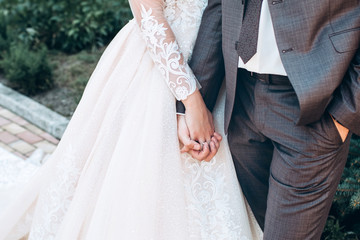 A young couple hold hands. lovers guy and girl walk in the summer in nature. The bride and groom. Hands close-up