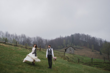 Fototapeta premium Romantic, young and happy caucasian couple in wedding clothes hugging on the background of beautiful mountains. Love, relationships, romance, happiness concept. Bride and groom traveling together.