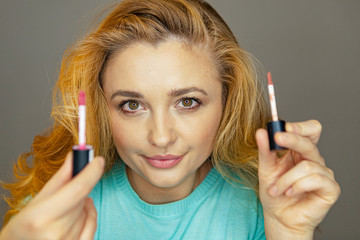 Obraz premium Beauty blogger is testing makeup. A young girl advises makeup.A girl is testing lip pencils and lipsticks. Beautiful woman paints her lips.