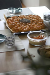 Various food served on a table: cake, homemade bread, crackers, hummus and strawberries. Vase with flowers defocused in the foreground. Selective focus.